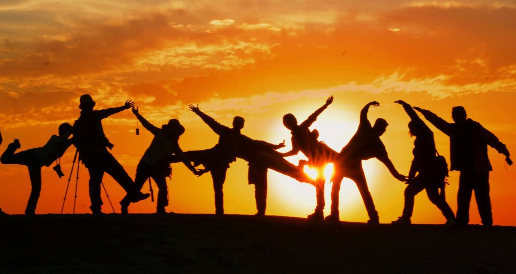 Group of people all being active in front of the sunset